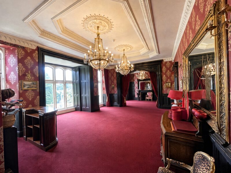 The Red Room, with red damask walls and twin chandeliers